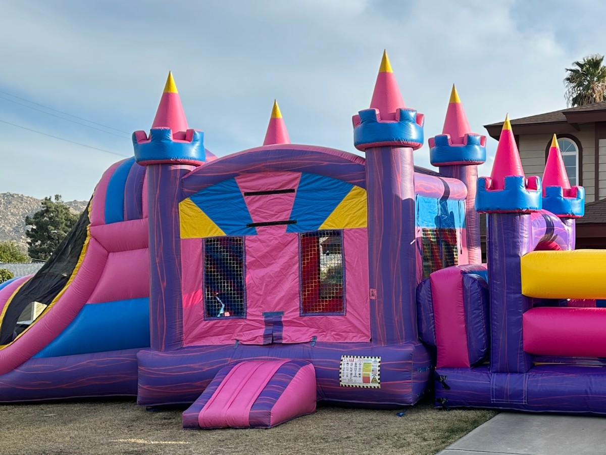 Rainbow inflatable bounce house set up for a backyard children’s party